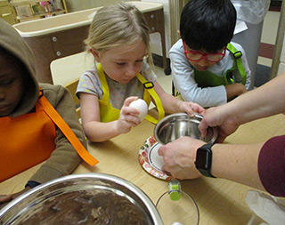 Students cracking eggs into a bowl
